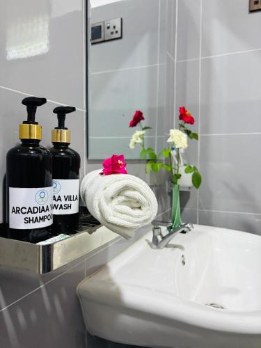 a bathroom sink with two bottles of soap and flowers at Arcadiaa Villa in Polonnaruwa