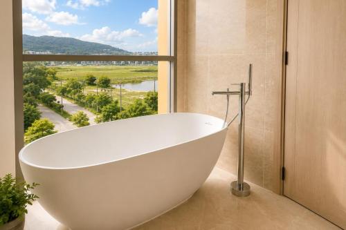 a bath tub in a bathroom with a large window at Modern 2BR Apartment with Golf View in Laguna Phuket - Condo Ozone 108-156 in Laguna Phuket