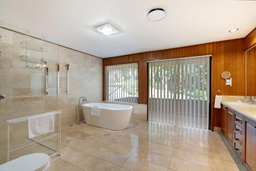 a bathroom with a tub and a shower and a sink at Kookaburra Retreat in Berkeley Vale