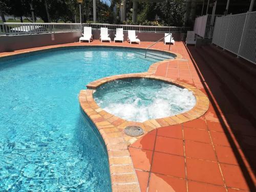 a large swimming pool with chairs at The Reef Motel in Cairns