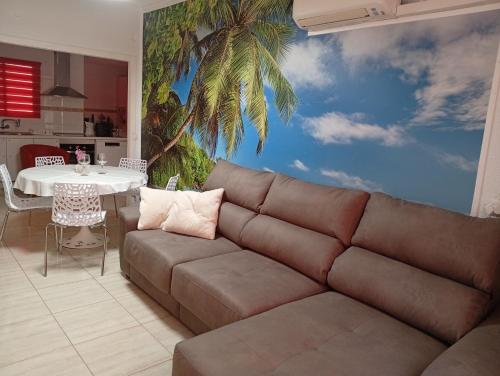 a living room with a couch and a palm tree mural at Alma Brizo Suites in Grao de Castellón