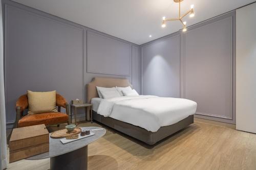 a bedroom with a bed and a chair and a table at Bergen Hotel Daejeon Yuseong in Daejeon