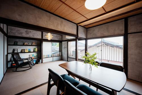 a dining room with a table and chairs and windows at 海と富士山を望む4名1棟貸し古民家宿 最大7名 鎌倉エリアの隠れ家 in Zushi
