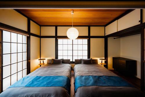 two beds in a room with two windows at 海と富士山を望む4名1棟貸し古民家宿 最大7名 鎌倉エリアの隠れ家 in Zushi