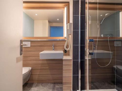 a bathroom with a sink and a mirror and a shower at IBIS STYLES ALES CENTRE in Alès