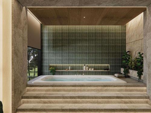 a jacuzzi tub in a bathroom with green tiles at Mövenpick Resort & Spa Bintan Lagoon in Lagoi