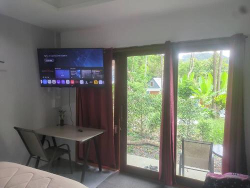 a room with a window and a table and a television at The Rendezvous Phangan in Ko Phangan