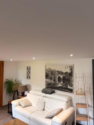 a living room with a white couch and a painting on the wall at Gite Climatisé Les Terrasses Perchées 2 Chambres in Saint-Vincent