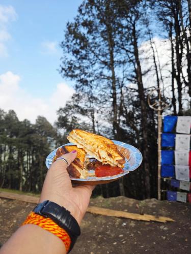 a person holding a plate with a slice of pizza at Raghupur trecking camp in Shoja
