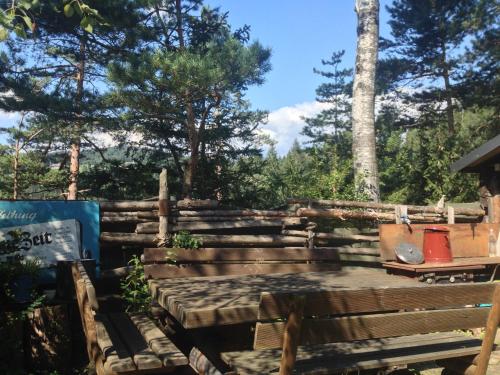 a wooden bench in a garden with trees in the background at Ferienhaus im Wald in Edelschrott