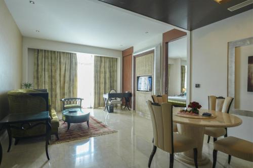 a living room with a table and a dining room at Le Meridien Jaipur Resort & Spa in Jaipur
