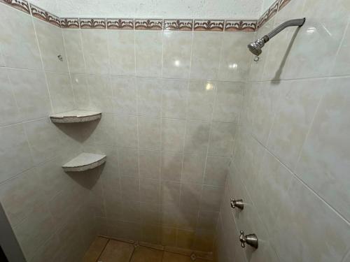 a white tiled bathroom with a shower with two shelves at Quinta Huicochea in Cuernavaca