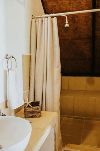 a bathroom with a shower curtain and a sink at Hotel Los Olivos La Playa in Escuintla