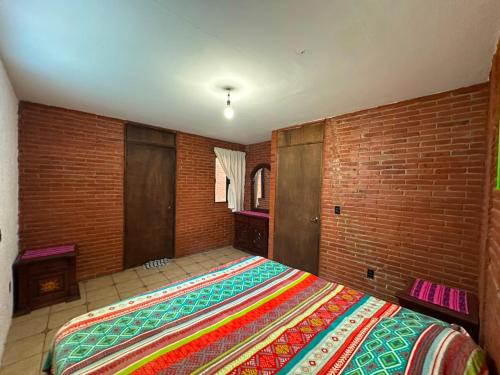 a bedroom with a large bed in a brick wall at Quinta Huicochea in Cuernavaca