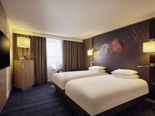 a hotel room with two beds and a tv at Mercure Le Havre Centre Bassin Du Commerce in Le Havre