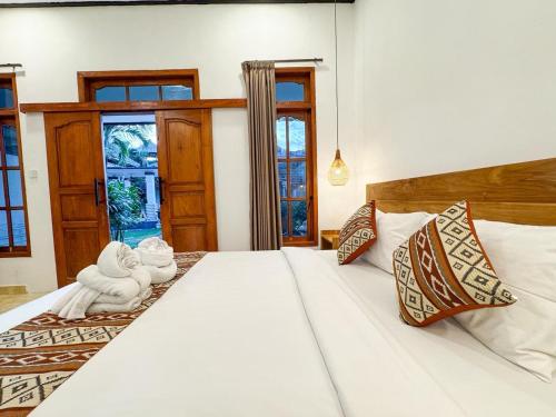 a bedroom with a large white bed with pillows at Mamo Hotel Uluwatu in Uluwatu