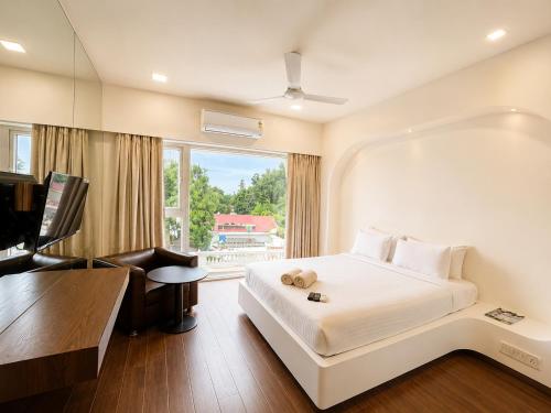 a bedroom with a bed and a desk and a television at Cosset - A Boutique Hotel in Lonavala