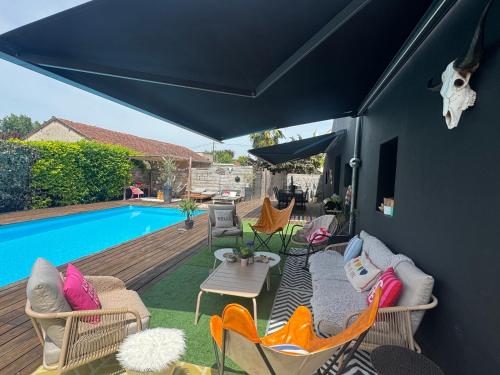 a patio with chairs and a table and a pool at La Villa d'ElodibiZa, 45mn de Paris en train avec piscine ! in Écuelles