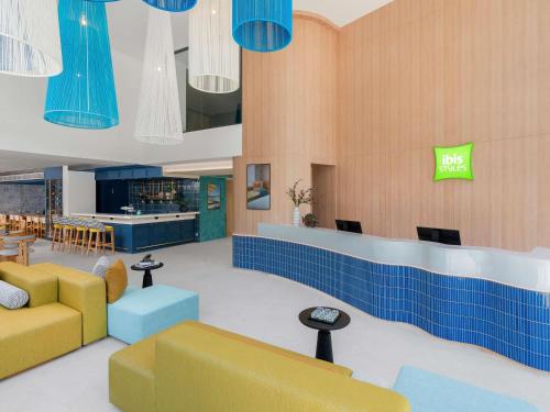 a lobby with blue and yellow furniture and a bar at ibis Styles Phuket Bangtao in Bang Tao Beach