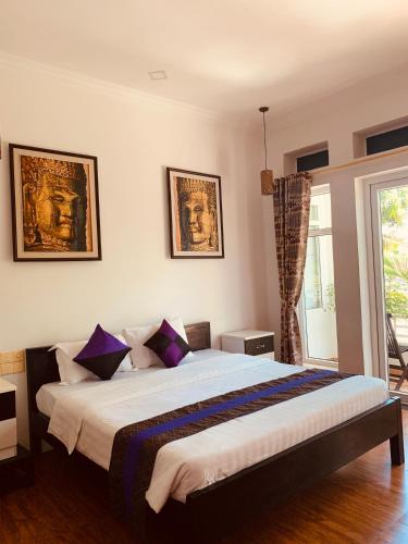 ein Schlafzimmer mit einem großen Bett und lila Kissen in der Unterkunft Saba Lua Siem Reap in Siem Reap