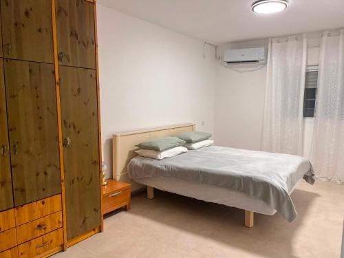 a bedroom with a bed and a wooden cabinet at בית בערבה in Mitzpe Ramon