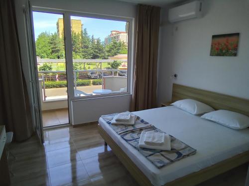 a bedroom with a bed and a large window at Family Hotel PUDEV in Sunny Beach