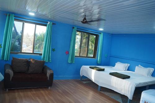 a blue room with a bed and a couch at Dr Vijeta's Wellness Retreat in Alībāg