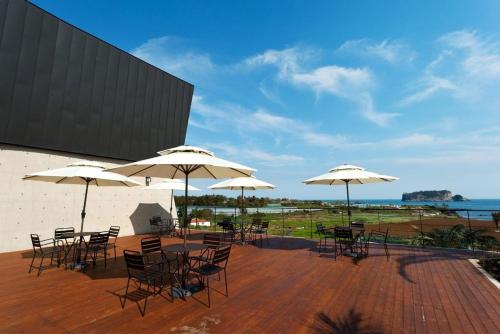 a patio with tables and chairs with umbrellas at The BB's Jeju Resort in Seogwipo