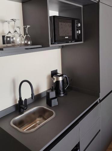 a kitchen counter with a sink and a microwave at Villa Vadori Suites in Falda del Carmen