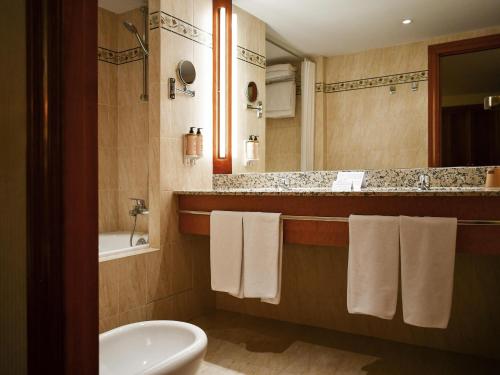 a bathroom with a sink and a toilet and a tub at Mercure Andorra in Andorra la Vella