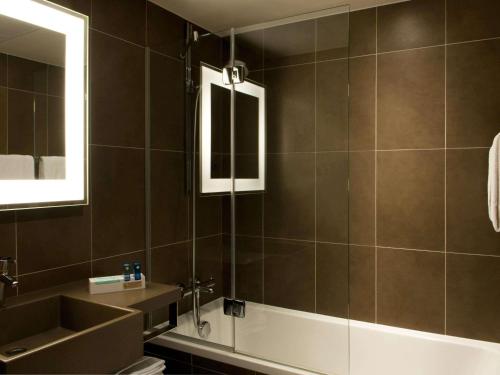 a bathroom with a sink and a tub and a mirror at Novotel Massy Palaiseau in Palaiseau