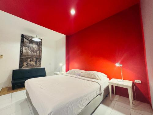 a bedroom with a red wall with a bed and a chair at Sino @ Thungsong in Thung Song