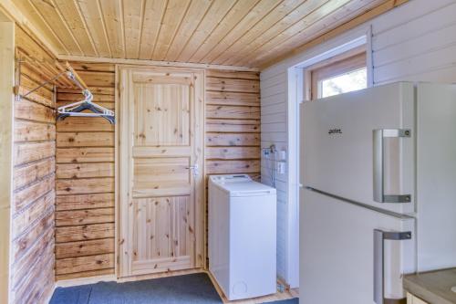 a kitchen with a washer and dryer and a refrigerator at Pinetree Cottages Sunny cabin in Pyhäranta