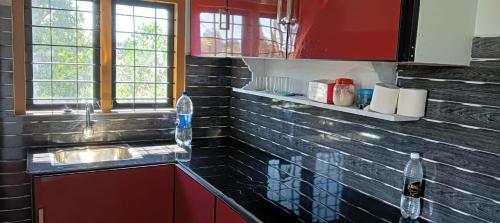 a kitchen with a sink and red cabinets and windows at Morning Glory in Vagamon