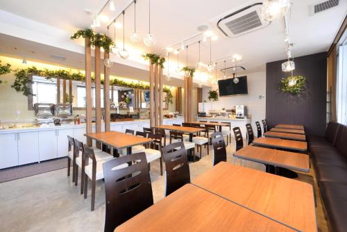 a restaurant with wooden tables and chairs and a kitchen at Vessel Inn Hiroshima Station in Hiroshima