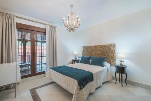 a bedroom with a bed with blue pillows and a chandelier at Hotel Amapola La Barrosa in Novo Sancti Petri