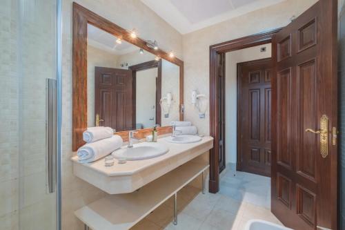 a bathroom with two sinks and a large mirror at Hotel Amapola La Barrosa in Novo Sancti Petri