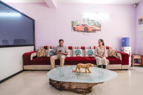 a man and woman sitting on a couch in a living room at FabHotel Shadowline in Goa