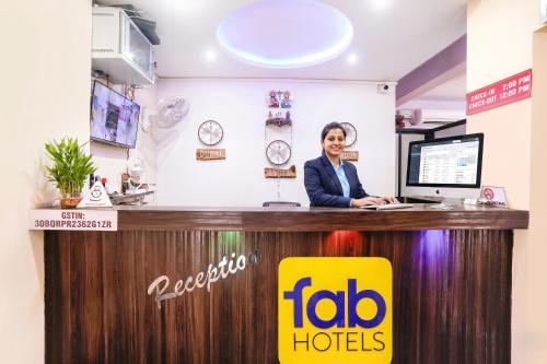 a woman is sitting at a reception desk at FabHotel Shadowline in Goa