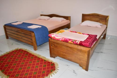 two beds and a rug in a room at Bhitarkania Riverside Eco Resorts in Righāgarh