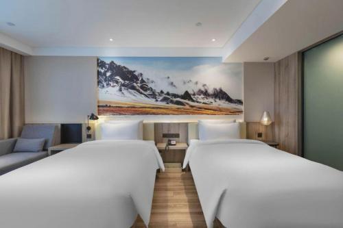 two beds in a room with a painting on the wall at Atour Hotel (Urumqi Renmin Cinema) in Ürümqi