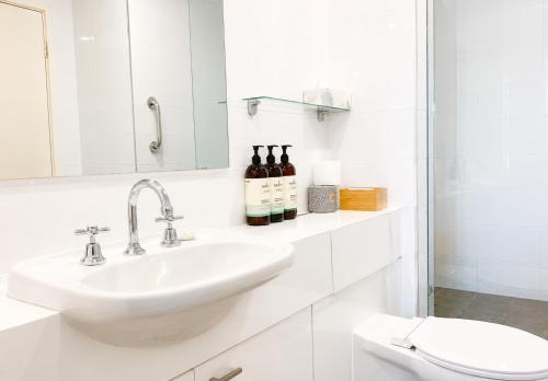 a white bathroom with a sink and a toilet at Esplanade Views Heart of Freo Family Stay in Fremantle