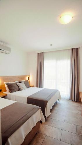 a hotel room with two beds and a window at Costa Sariyaz Hotel Bodrum in Bodrum City