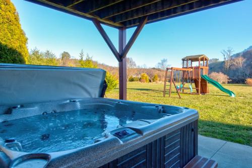 a hot tub on a patio with a playground at New River Ramble in Todd