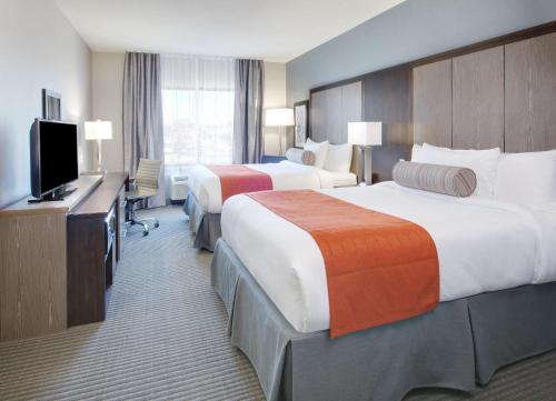 a hotel room with two beds and a flat screen tv at Wingate by Wyndham San Angelo in San Angelo