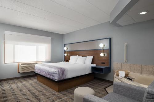 a hotel room with a bed and a tub at AmericInn by Wyndham Baldwin in Baldwin