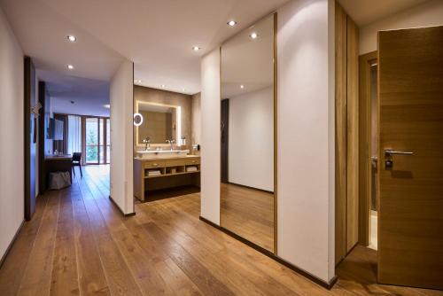 a hallway with a bathroom with a sink and a mirror at Das Kronthaler - Adults only in Achenkirch