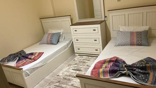 two twin beds in a bedroom with a dresser at Laserina North Coast in Zāwiyat ‘Abd al Mun‘im