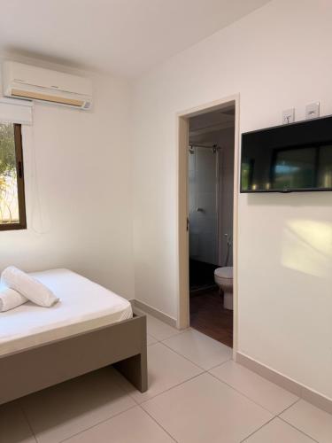 a white room with a bed and a bathroom at Flat Hotel Canarius Gravatá in Gravatá
