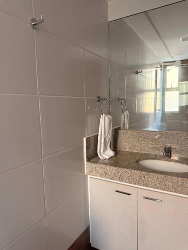 a white bathroom with a sink and a mirror at Flat Hotel Canarius Gravatá in Gravatá